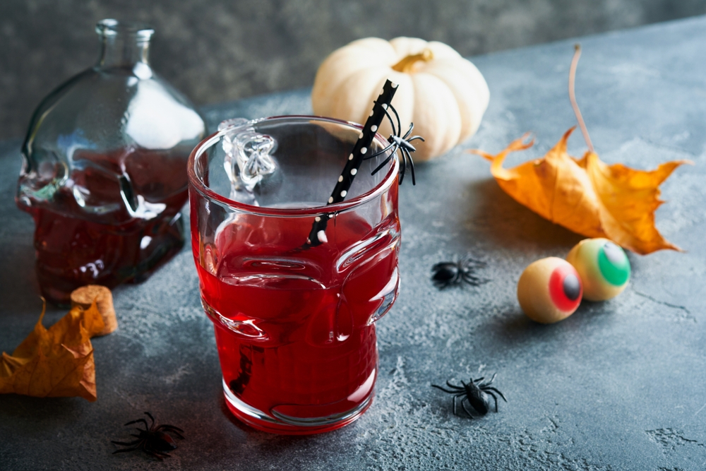 Halloween-themed cocktail with skull glass, plastic spiders, and pumpkins symbolizing the dangers of drunk driving and DUI accidents.