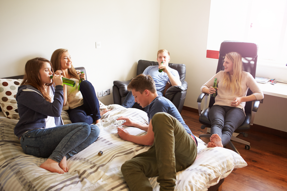 College students drinking alcohol at a dorm party, a common situation that can lead to an underage drinking arrest.