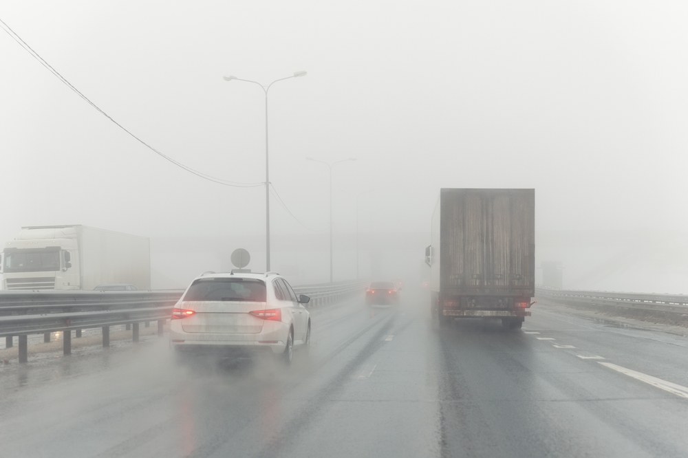 Cars driving in heavy rain and fog on highway, illustrating hydroplaning risks and wet road car accidents