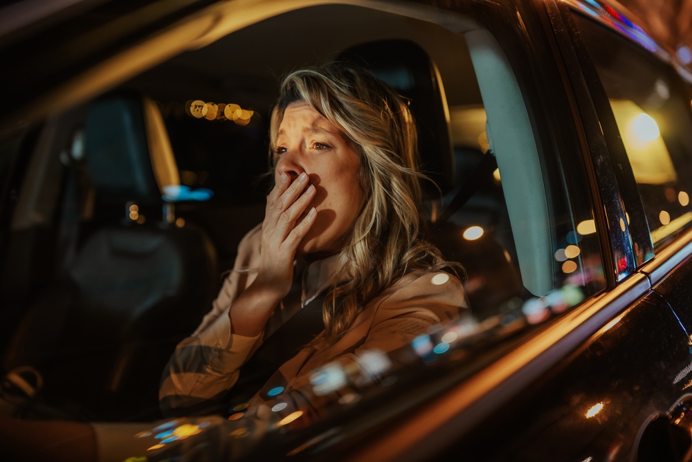 Woman driving at night looking shocked during stressful commute after daylight saving time change