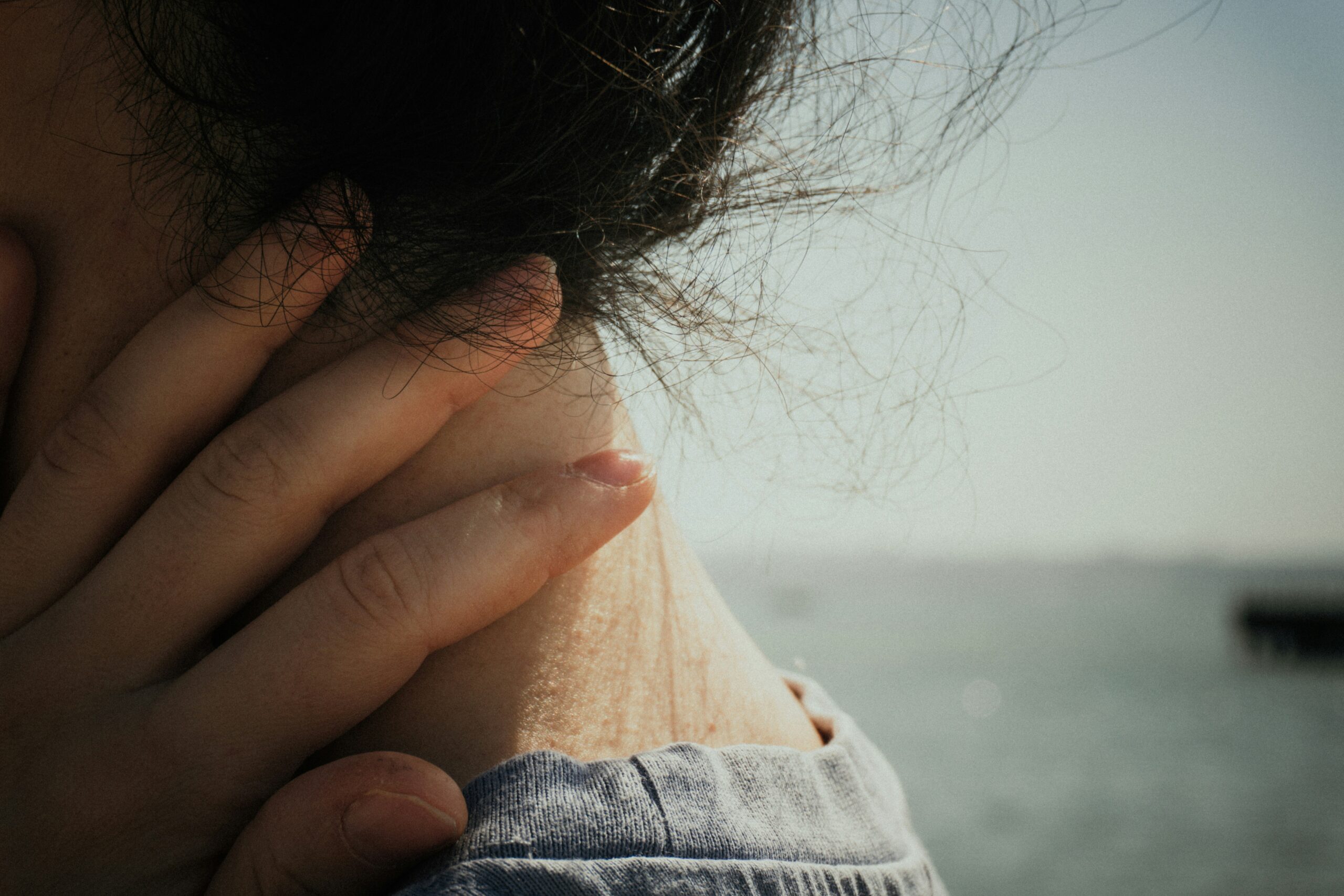Person holding neck in pain, representing symptoms of delayed head and neck cancer diagnosis