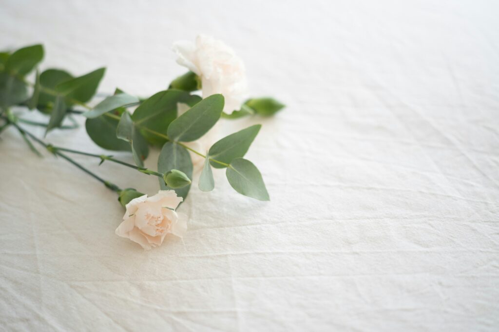Soft white carnations and eucalyptus resting on linen, a quiet tribute for families learning how a survival action can honor a loved one.
